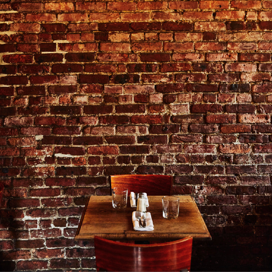 A vacant table in a restaurant, set with two glasses and an elegant napkin placed at the center.