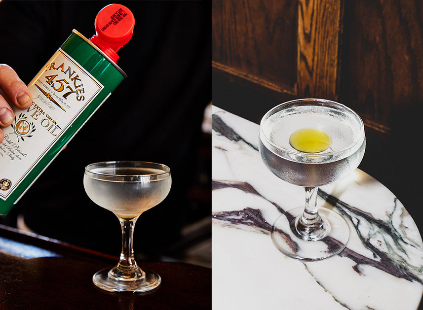 Side-by-side images of a cocktail in a coupe glass. On the left, a hand is pouring Frankies 457 Extra Virgin Olive Oil from a green can into the drink. On the right, the finished cocktail sits on a marble surface with a golden pool of olive oil floating on top